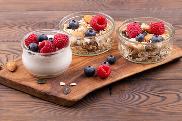 Healthy breakfast with yogurt and raspberries, blueberries, homemade muesli with nuts, on a wooden rustic table