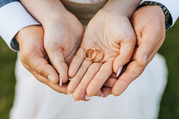 The bride and groom hold round gold rings in their hands, close-up on the palms. Wedding portrait, photography, concept.