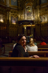 Woman is sitting in dark church interior, Montserrat, Barcelona.