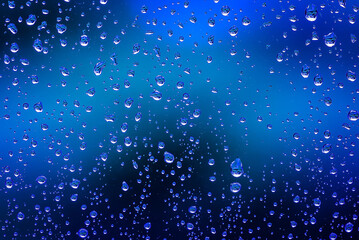 Naklejka na ściany i meble Raindrops on a window in blue close up