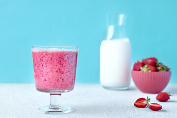 Strawberry coconut milkshake, frappé or smoothie in drinking glass on light blue background. Healthy vegan diet refreshing drink. Healthy food and drink concept.