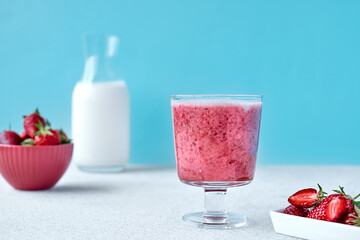 Strawberry coconut milkshake, frappé or smoothie in drinking glass on light blue background. Healthy vegan diet refreshing drink. Healthy food and drink concept.