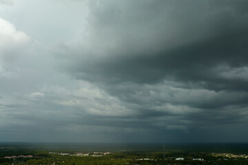 Fototapeta na wymiar Dark stormy clouds forming on gloomy sky before heavy rainfall over suburban town area