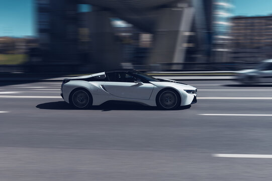 BMW i8 plug-in hybrid car is moving along the street with blurred urban background