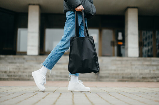 Stylish woman in bloodstains and jeans with a bag in hand, close photo of legs.