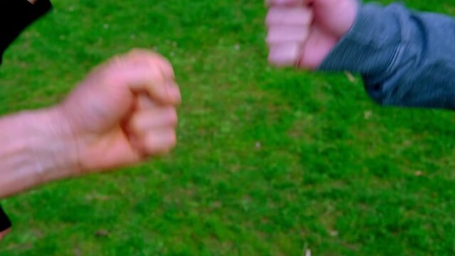 close-up of male, female hands against background of green grass, playing game of rock, paper, scissors, concept of a meeting of friends, joy of communication in informal setting, Hanging out