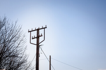 Old power electric with a power supply cable and ceramic insulators, made of an obsolete connection system to the public network of electricity taken during a sunny afternoon.....