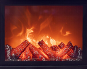 The logs of the fireplace burn with a bright fire. Artificial decorative fireplace with imitation...