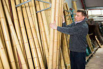 Young man choosing bamboo stakes at garden material store