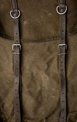 Close-up texture of a canvas fabric backpack. Leather straps and metal buckles. Vintage khaki back.