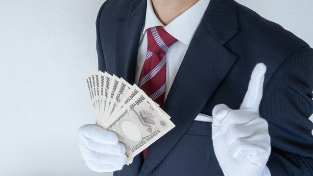白手袋をはめて現金を数えるスーツ姿の男性│買取り査定イメージ