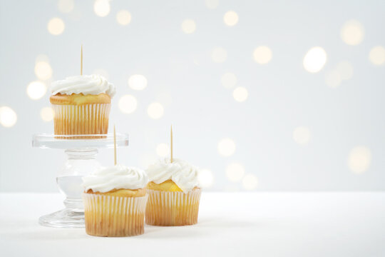 Vanilla White Cupcake Topper Mockup. Styled against a white background with bokeh party fairy lights. Copy space for your design here.
