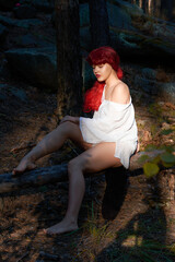 a girl with red hair and a white shirt with a rose in her hands is resting in a fabulous forest.
