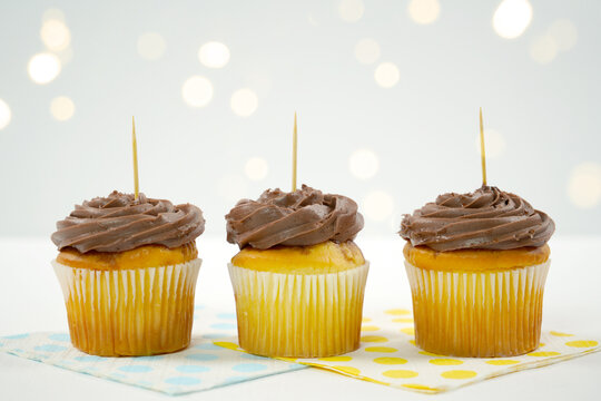 Three Chocolate Cupcakes Topper Mockup. Styled against a white background with bokeh party fairy lights. Copy space for your design here.