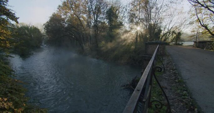 The first sun shine through the trees on the river Lambro in Italy during a cold morning in autumn