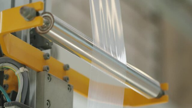 Multilayer plastic film rolling on the machine at the factory. Goods and products packaging, industrial automation, plastic themes. Sealability.