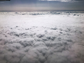 Flying above clouds and cloudscape from a plane window.