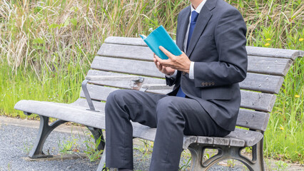 ベンチで本を読むビジネスマン