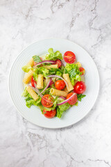 Lettuce tomato cherry salad with penne pasta.