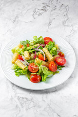 Lettuce tomato cherry salad with penne pasta.