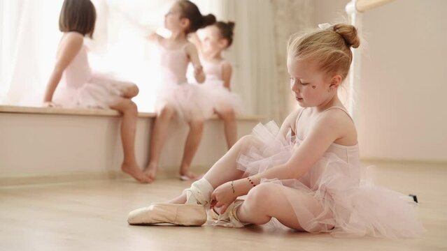 Stretching exercises. Team of little ballerinas have practice session indoors
