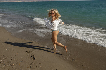 Contented woman laughing while running along the sea shore on summer vacation