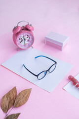 Product Presentation of Minimalist Concept Idea. glasses, gift box, clock and dry leaves on pink paper background.