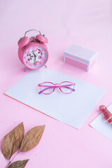 Product Presentation of Minimalist Concept Idea. glasses, gift box, clock and dry leaves on pink paper background.