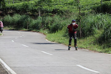 an Asian man in red who was learning to use roller skates on a concrete road with a panoramic view...