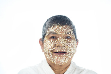 facial care Elderly latin woman applying an oatmeal mask to her face