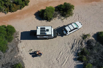 Australian couple relaxing during a beach holiday with 4WD vehicle and caravan - obrazy, fototapety, plakaty
