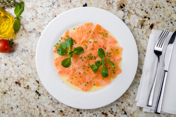 Salmon carpaccio on a white plate on marble table top view - 504290169
