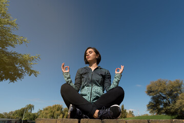 young and sexy woman in sporty clothes doing yoga in the park with lake behind, h, concept of physical activity and good life, selective focus, space for copy