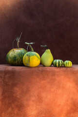 Still life with five different pumpkins on a brown background