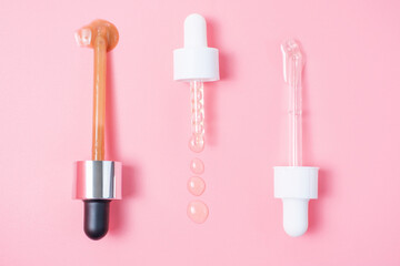 Three pipettes with serum and collagen on a pink background close-up.