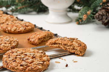 Freshly baked oatmeal cookies with sunflower seeds are cooling on a tray. The concept of simple homemade baking for the new year or Christmas, the idea of a healthy diet. Close-up, soft focus