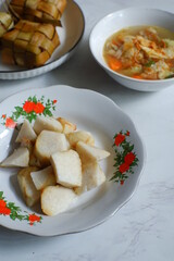 a plate of rice cake or ketupat served with vegetable soup