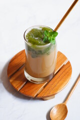 a glass of iced coffee with green grass jelly 