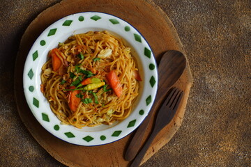 a plate of noodles cooked in sauce with vegetables 