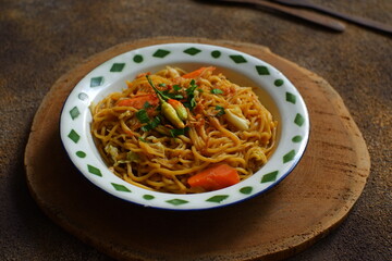 a plate of noodles cooked in sauce with vegetables 