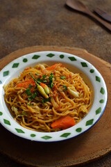 a plate of noodles cooked in sauce with vegetables 