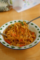 a plate of noodles cooked in sauce with vegetables 