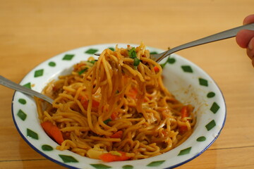 a plate of noodles cooked in sauce with vegetables 