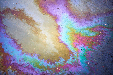 Oil stain on the asphalt, rainbow-shaped colored gasoline stains on an asphalt road as a texture or background