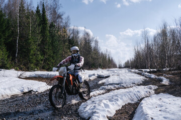 Rider riding  motocross motorcycle on  snowy off-road on  summer day in mountains