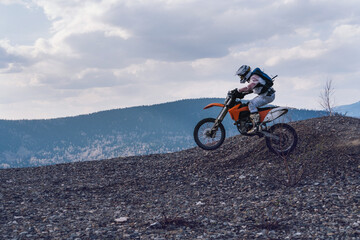 Obraz premium Motorcyclist jumping on motorcycle on mountain top with stunning views of mountains valley