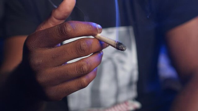 African american man holding a lit marihuana joint 