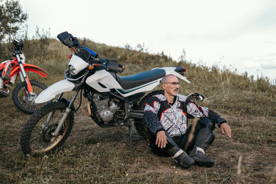  60 year old active athlete motorcyclist wearing moto gear sitting near motorcycle