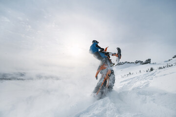 Silhouette of Jumping Snowbike driver in mountain valley in beautiful snow powder during sunse