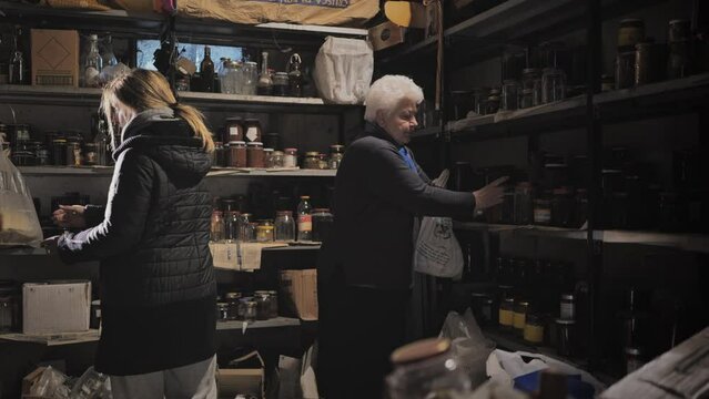 War,caucasian old woman and daughter store food supplies in the basement shelter,family worried from the coming war stocking food reserves in the bunker